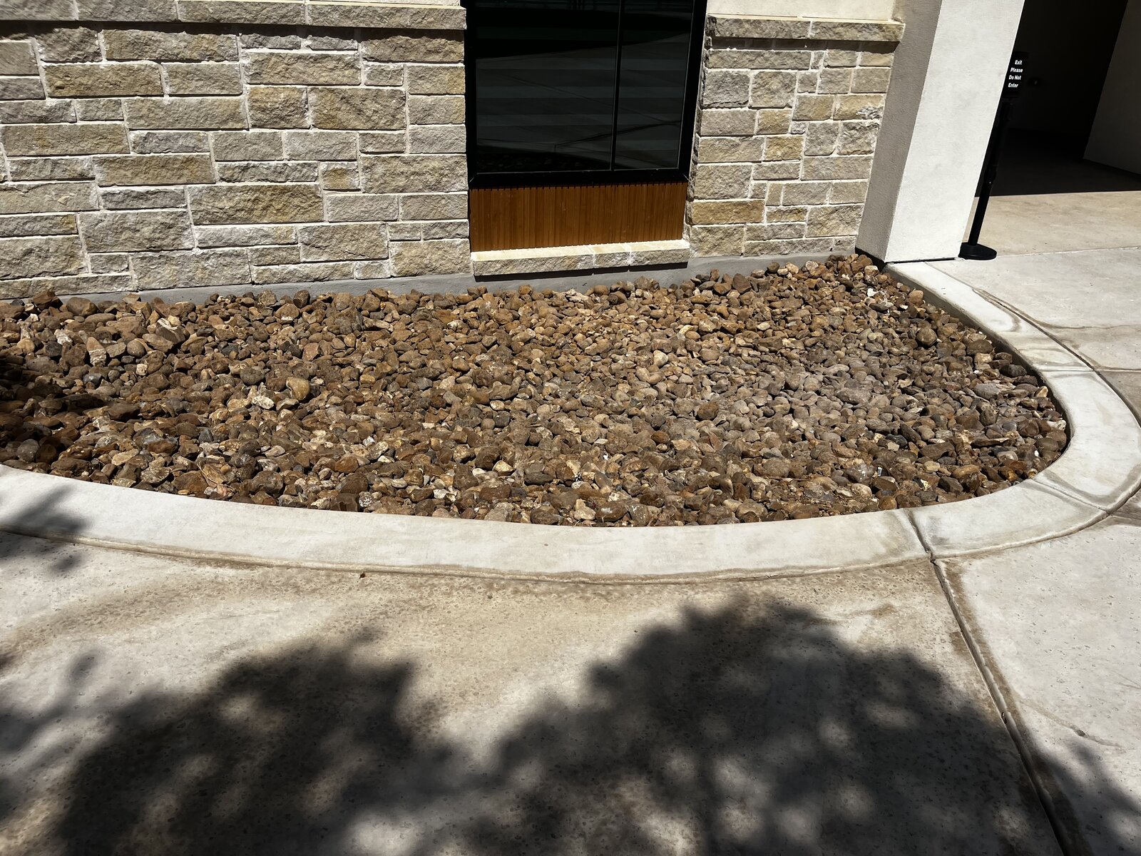 River rock xeriscape bed along stone wall
