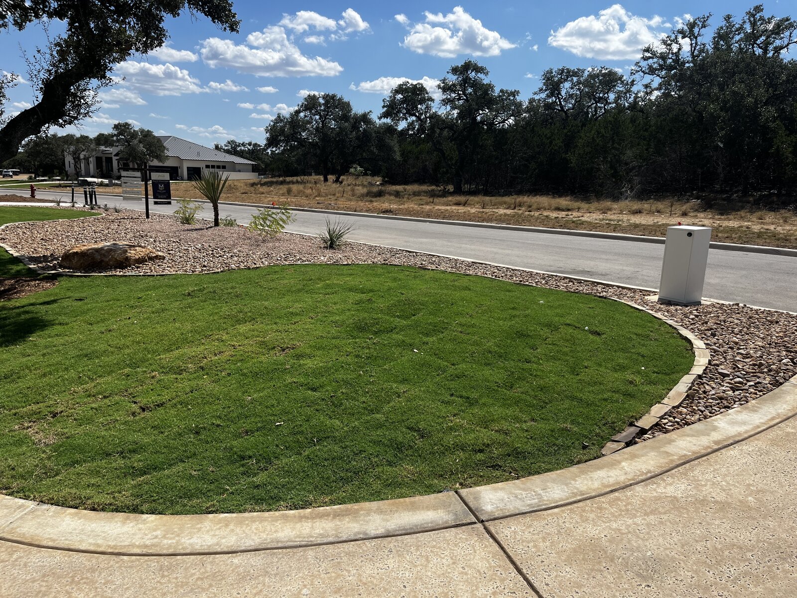 Curved sod island bordered by river rock