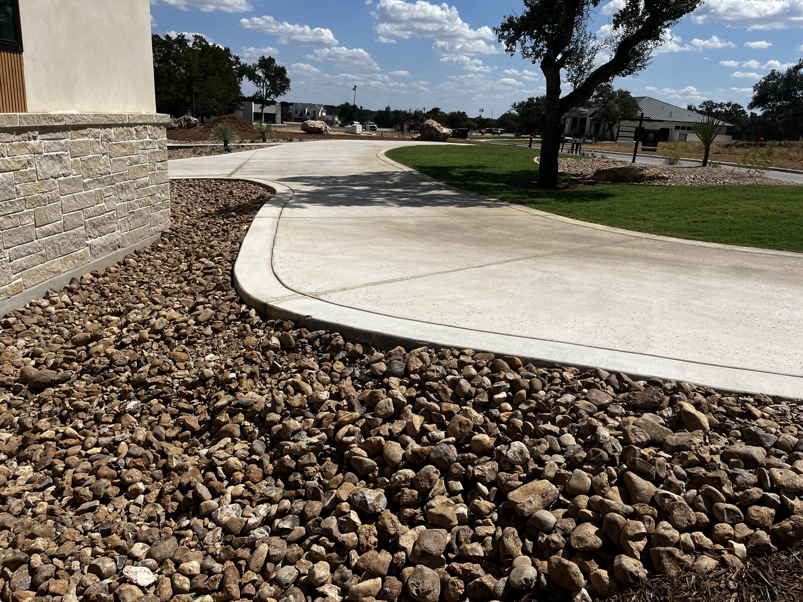 River rock bed, curved concrete, and fresh sod