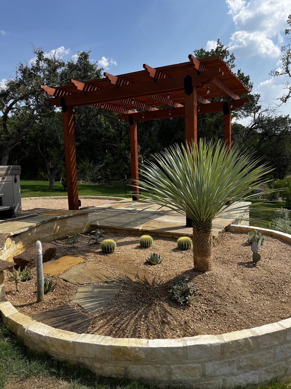 Wooden pergola with string lights over a flagstone patio and Texas xeriscape garden — Texas Tough Landscapes
